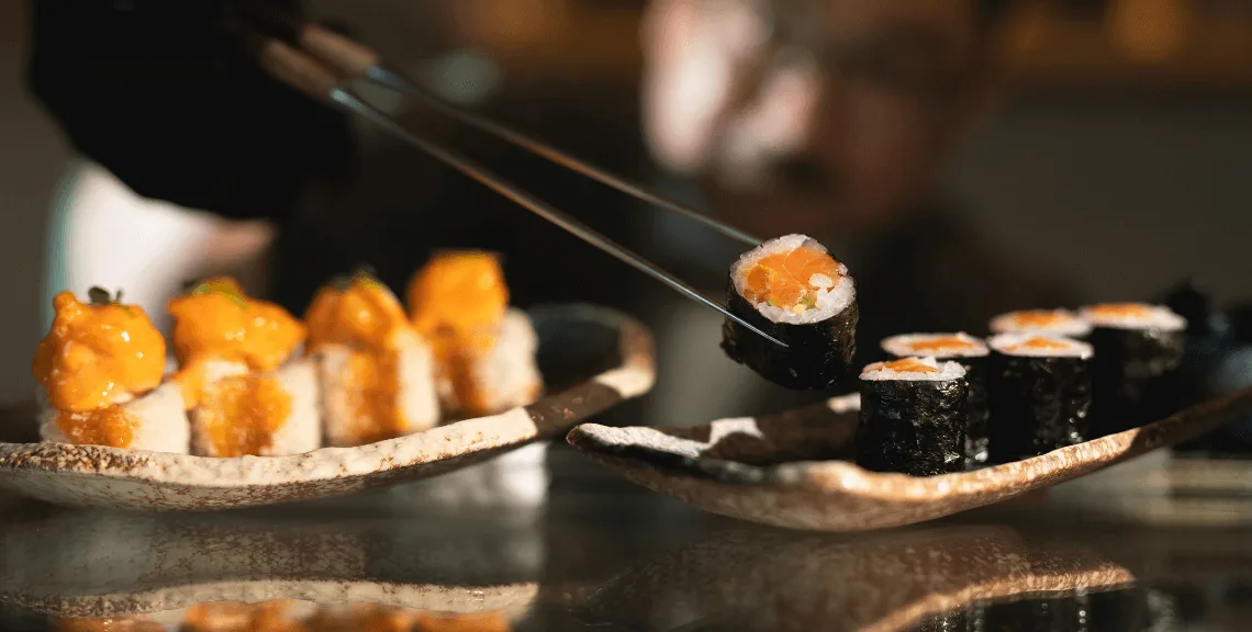 Sushi maki rolls picked up by sticks